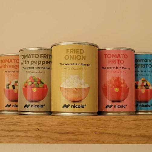 Four small cans of Nicola Fried Onion in Olive oilother sauces lined up on a wooden shelf against a beige wall. The cans feature colorful labels for various tomato-based and onion-based fried foods.
