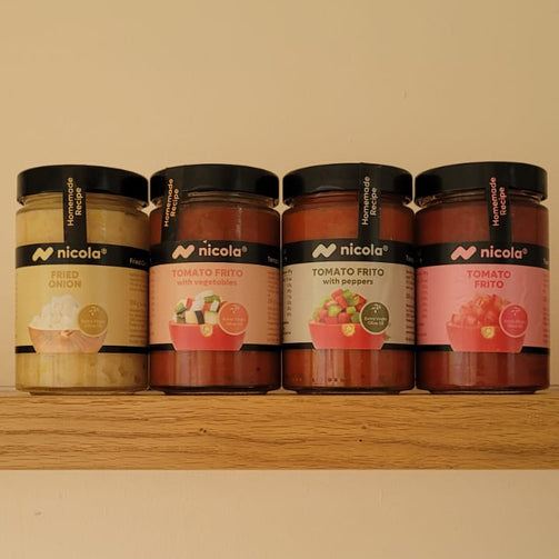 Four jars of Nicoça jam arranged on a wooden shelf against a plain beige wall. The jars contain different colored jams: beige, reddish-brown, and pinkish-red, with black lids and white labels featuring the Nicoça brand.
