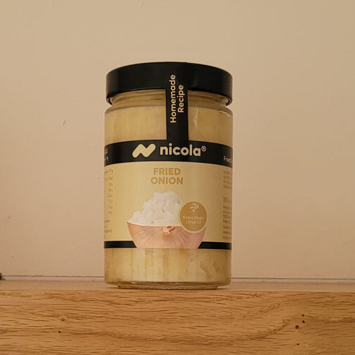 A jar of Nicola Fried Onion spread sitting on a wooden shelf against a plain beige wall.